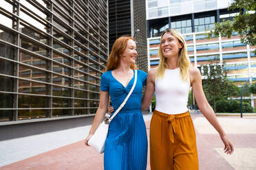 Glückliche Frauen, die gemeinsam vor dem Gebäude spazieren gehen - OIPF02081