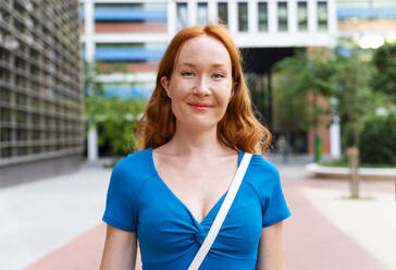 Smiling redhead woman by building in city - OIPF02082