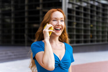 Glückliche Frau, die in der Stadt mit einem Mobiltelefon spricht - OIPF02102
