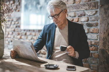 Businessman reading newspaper and having coffee in cafe - JOSEF11519