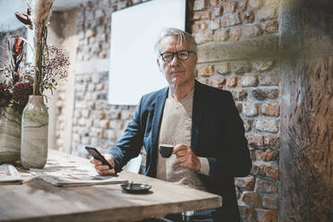 Geschäftsmann mit Smartphone bei einem Kaffee im Café - JOSEF11521