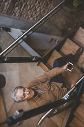 Senior man with smart phone sitting on staircase - JOSEF11530