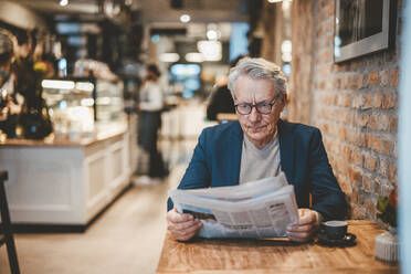 Senior businessman reading newspaper in cafe - JOSEF11549