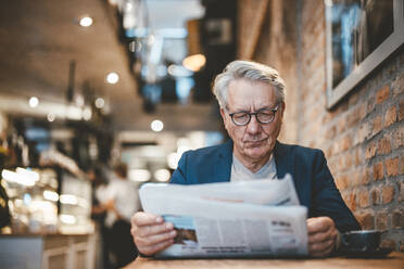 Businessman reading newspaper in cafe - JOSEF11550