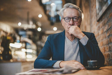 Senior businessman with hand on chin in cafe - JOSEF11554