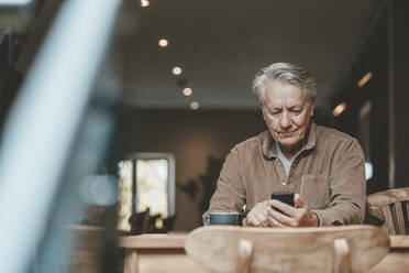 Senior man using smart phone in cafe - JOSEF11558