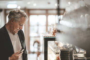 Geschäftsmann mit Smartphone im Cafe - JOSEF11584
