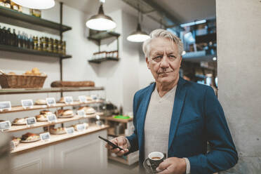 Älterer Geschäftsmann mit Kaffeetasse und Mobiltelefon in einem Cafe - JOSEF11592