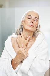 Woman with eyes closed massaging neck in bathroom - VEGF05781