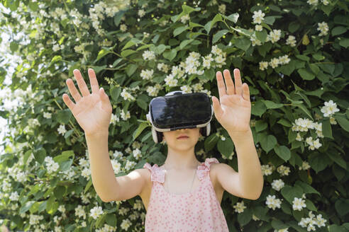 Mädchen mit Virtual-Reality-Simulator vor einer blühenden Pflanze - OSF00456