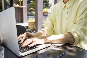 Hands of freelancer using laptop at sidewalk cafe - OSF00460