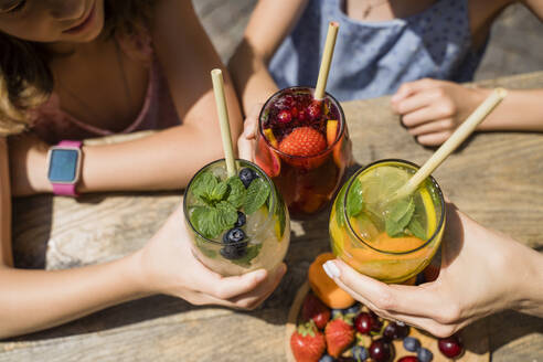 Hände von Frauen und Mädchen, die mit Strohhalmen auf Cocktails anstoßen - OSF00467