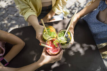 Hände von Mädchen und Frauen, die mit Strohhalmen auf Cocktails anstoßen - OSF00471