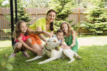 Playful mother and daughters with dog at back yard - OSF00478