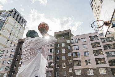Man throwing basketball in hoop on sunny day - VPIF06868