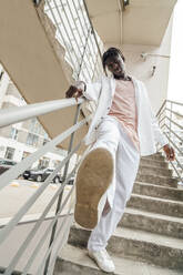 Young man standing on steps by railing - VPIF06892