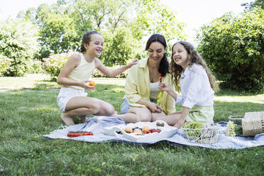 Happy daughters having picnic with mother at park on weekend - OSF00500