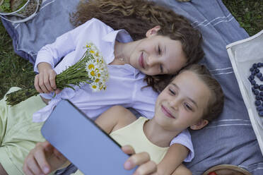 Lächelnde Mädchen nehmen Selfie auf Smartphone im Park liegend - OSF00511