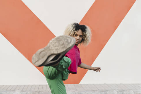 Young woman kicking in front of wall - JCCMF06779