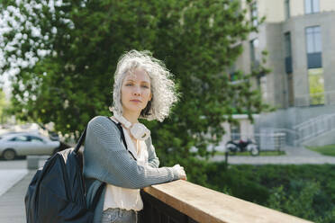 Woman with backpack leaning on railing - SEAF01051