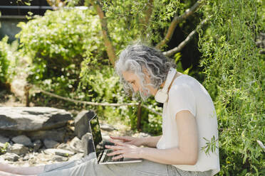 Freiberufler mit Laptop bei Pflanzen im Park - SEAF01081