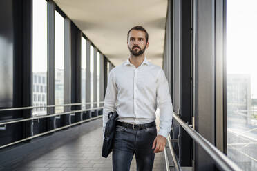 Junger Geschäftsmann mit Tasche auf erhöhtem Gehweg - DIGF18372