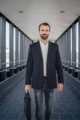 Smiling businessman standing on elevated walkway - DIGF18385