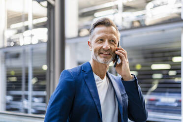 Lächelnder reifer Geschäftsmann im Gespräch mit einem Smartphone - DIGF18389