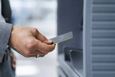 Hand of businessman holding credit card near ATM machine - DIGF18429