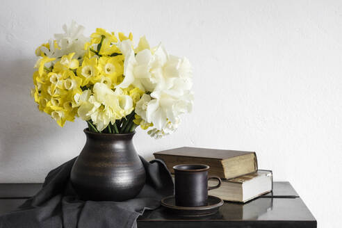 Studio shot of vase with blooming daffodils standing on rustic table - EVGF04041