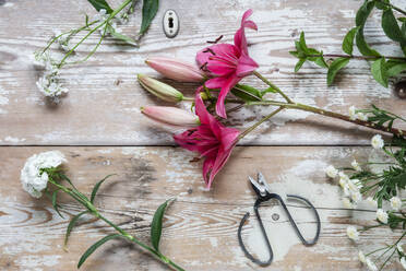 Pair of scissors and freshly cut flowers lying on wooden surface - EVGF04046