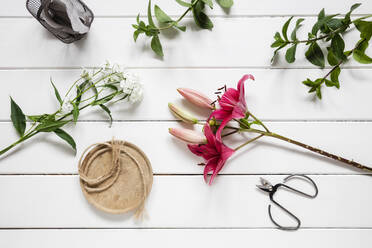 Pair of scissors and freshly cut flowers lying on wooden surface - EVGF04047
