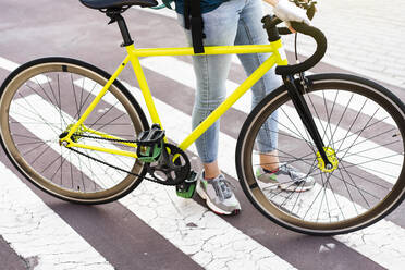 Lieferfrau mit Fahrrad auf Zebrastreifen stehend - DAMF01054