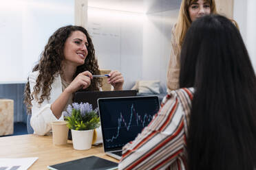 Geschäftsfrauen treffen sich in einem Büro mit einer Tabelle auf einem Laptop-Display - PNAF04156