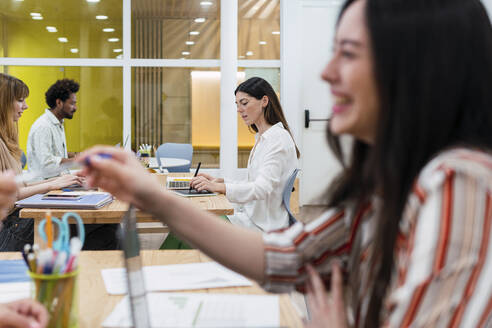 Businesswoman handing over pen to colleague in office - PNAF04235