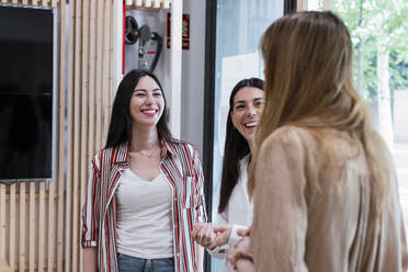 Drei glückliche Geschäftsfrauen im Gespräch im Büro - PNAF04257