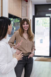 Two happy businesswomen talking in office - PNAF04262