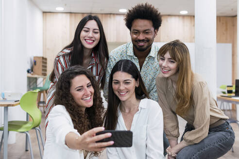 Lächelndes Geschäftsteam macht Selfie im Büro - PNAF04266