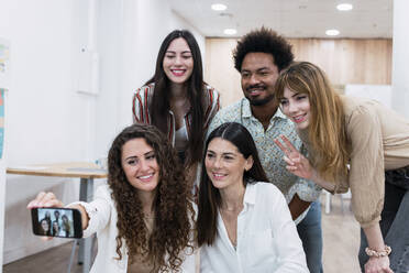 Lächelndes Geschäftsteam macht Selfie im Büro - PNAF04268