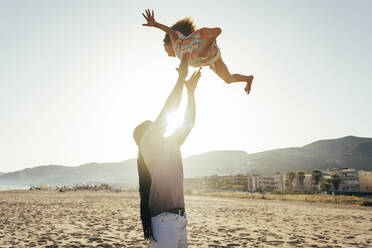 Playful father throwing daughter in air at beach - OIPF02120