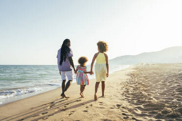 Mann mit Töchtern spazieren am Strand an einem sonnigen Tag - OIPF02125