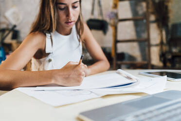 Fashion designer drawing on paper at desk - MEUF07315