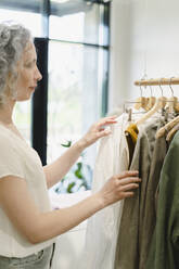 Woman choosing shirt at store - SEAF01098