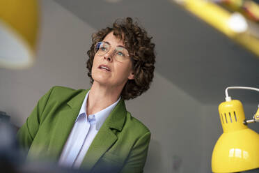 Businesswoman with brown curly hair wearing eyeglasses in office - JOSEF11665