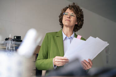 Thoughtful businesswoman with documents in office - JOSEF11669