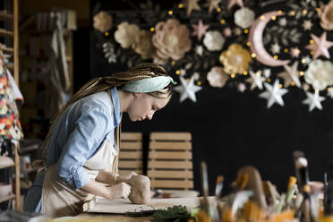 Kunsthandwerker knetet Ton auf einer Werkbank im Kunstatelier - LLUF00794