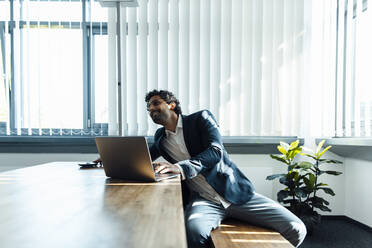 Businessman with laptop on desk at workplace - JOSEF11771