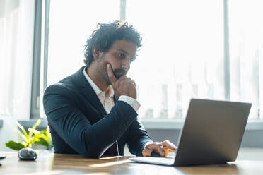 Geschäftsmann arbeitet am Laptop am Schreibtisch im Büro - JOSEF11829