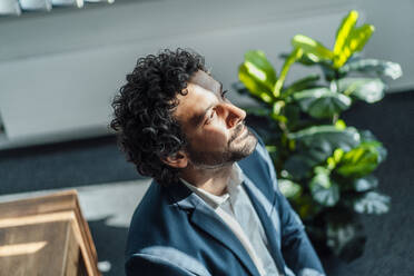 Thoughtful businessman with sunlight on face at workplace - JOSEF11833