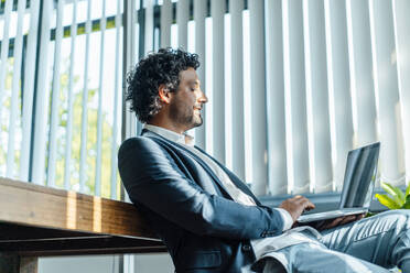 Geschäftsmann mit Laptop bei der Arbeit im Büro - JOSEF11834